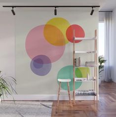 a living room with a book shelf and colorful circles wall mural on the wall behind it