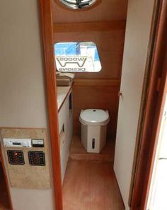 the inside of a small boat with wood flooring and white appliances on it's walls