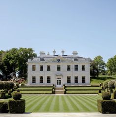 a large white house surrounded by hedges and trees