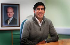 a man sitting at a desk in an office with a portrait on the wall behind him