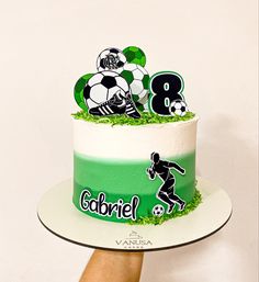 a person holding a cake with soccer decorations on it and the number 8 on top