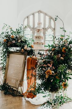 a wedding cake and flowers on display in front of a large window with a sign