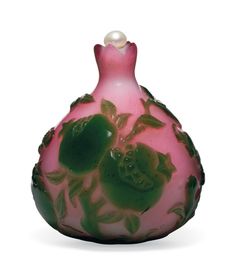 a pink and green vase with flowers painted on the side, sitting against a white background