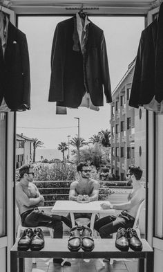 two men sitting at a table with shoes hanging from the clothes line in front of them