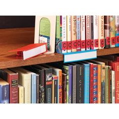 a book shelf filled with lots of books on top of a wooden table next to other books