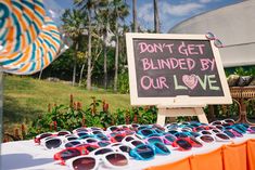 a sign that says don't get blinded by our love with many pairs of sunglasses