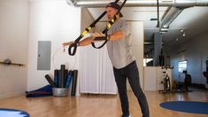 a man is doing aerial exercises on a rope in a room with other exercise equipment