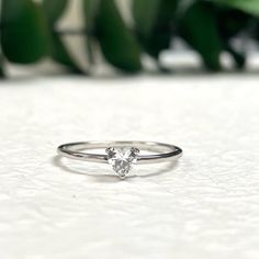 a white diamond ring sitting on top of a table next to a green potted plant