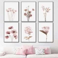 four pink flowers are hanging on the wall above a white couch in this living room