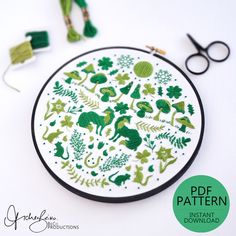 an embroidery pattern is shown with scissors, thread and sewing needles on the table next to it