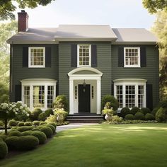 a green house with black shutters and white trim on the front door is shown