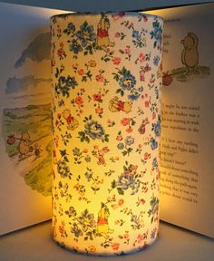 an open book with a lit up lamp in it's corner and winnie the pooh cover