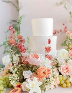 a wedding cake with flowers and fruit on the table