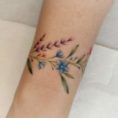 a woman's arm with blue flowers and green leaves on the left side of her body