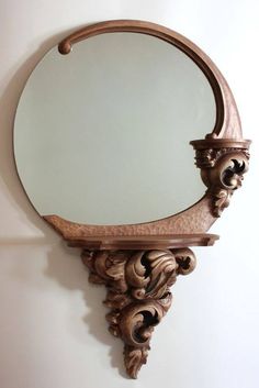 a mirror mounted to the side of a wall next to a wooden frame with carvings on it