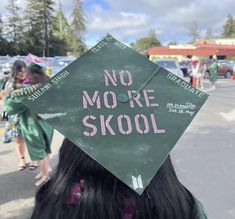 a girl wearing a green graduation cap with the words no more skool written on it