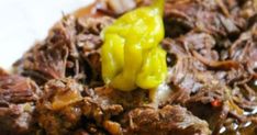 a close up of food on a plate with meat and vegetables in sauce, including peppers