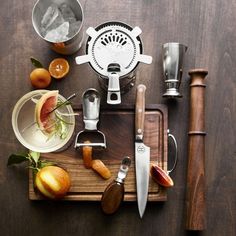 an assortment of kitchen utensils and fruit on a cutting board with knifes