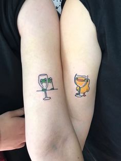 two people with matching tattoos on their arms, one has a glass of wine and the other has a toaster