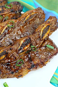 grilled meat on a white plate with green onions