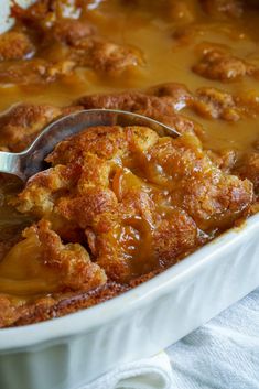 a close up of a spoon in a casserole dish with meat and gravy