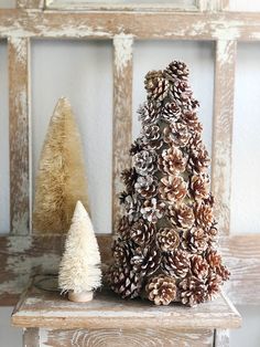 two pine cones are sitting on a table next to a small white cone christmas tree