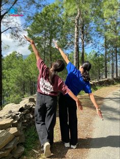 two people standing on the side of a road reaching up to catch a frisbee