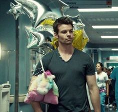 a man is walking down the hallway with balloons on his head and stuffed animals in his hand