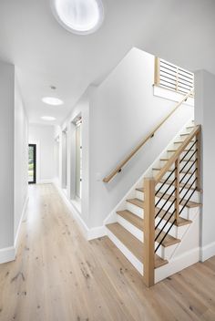 an empty room with white walls and wooden floors, stairs leading up to the second floor