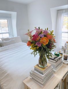 a vase filled with lots of flowers sitting on top of a table next to a bed