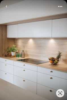 a kitchen with white cabinets and wooden counter tops, plants on the stove top in front of the sink