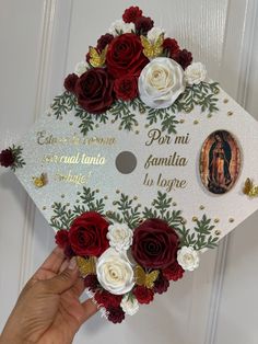 someone is holding up a graduation cap decorated with flowers and an image of the virgin mary