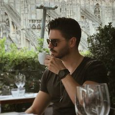 a man sitting at a table drinking from a cup