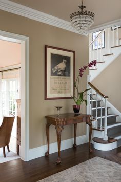 a room with a staircase, table and flowers on the table in front of it