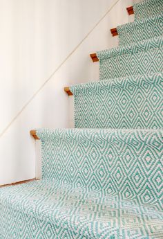 the carpeted stairs are lined with blue and white patterned rugs, along with wooden handrails