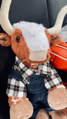 a stuffed cow wearing overalls and a white hat sitting in the back seat of a car