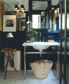 a white sink sitting under a bathroom mirror next to a black and white tiled floor