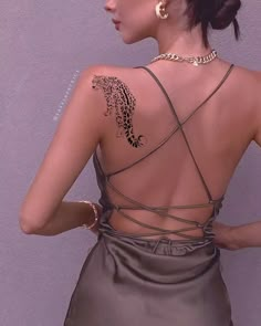 the back of a woman's dress with tattoos on her upper and lower back