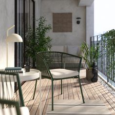 two chairs and a table on a wooden deck with potted plants in the background