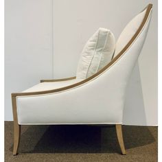 a white chair with gold trim on the arm and back, sitting against a wall