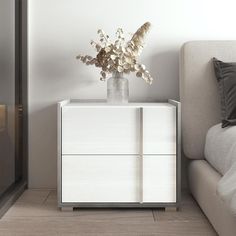 a vase with flowers sitting on top of a white cabinet next to a couch in a living room