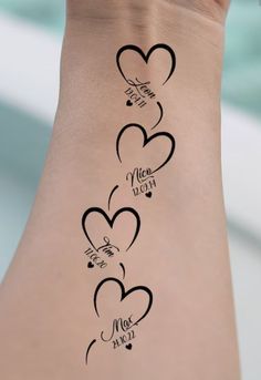 the back of a woman's arm with three hearts and two words on it