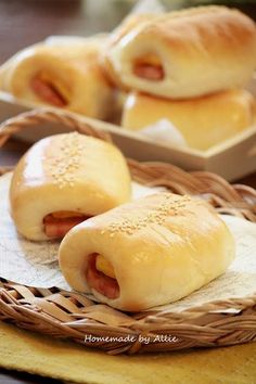 two hotdogs in buns on a plate next to a bowl of bread