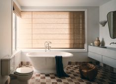 a white bath tub sitting next to a toilet under a window with shades on it