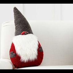 a gnome pillow sitting on top of a white couch next to a red and gray stuffed animal