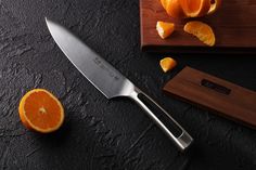 a large knife sitting on top of a cutting board next to sliced oranges and chopping block