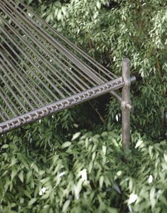 a metal hammock sitting in the middle of some bushes