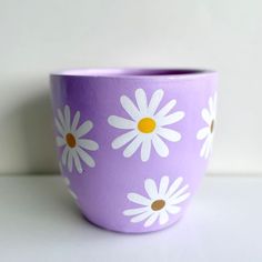 a purple flower pot with white daisies painted on it