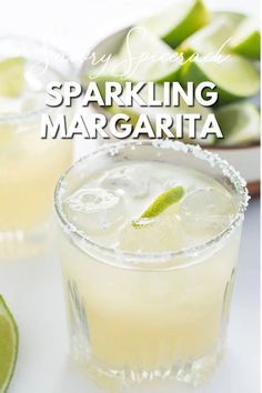 two glasses filled with sparkling margaritas on top of a white table next to lime slices