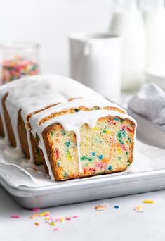 a cake with white icing and sprinkles on it sitting on a plate